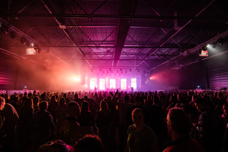 Een zaal vol met mensen bij een evenement Pump up the 90's.