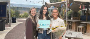 Drie vrouwen vieren certificering met bloemen en certificaat