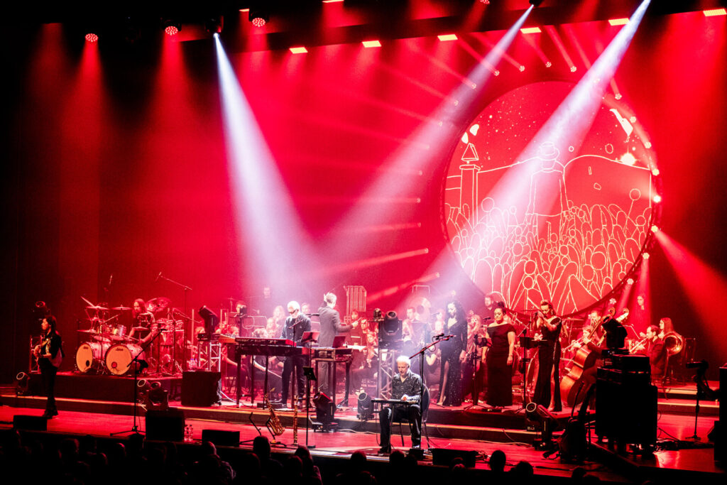 Orkest en band treden op onder rood podiumlicht