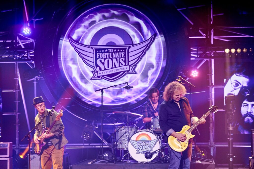 The Fortunate Sons spelen live op paars verlicht podium