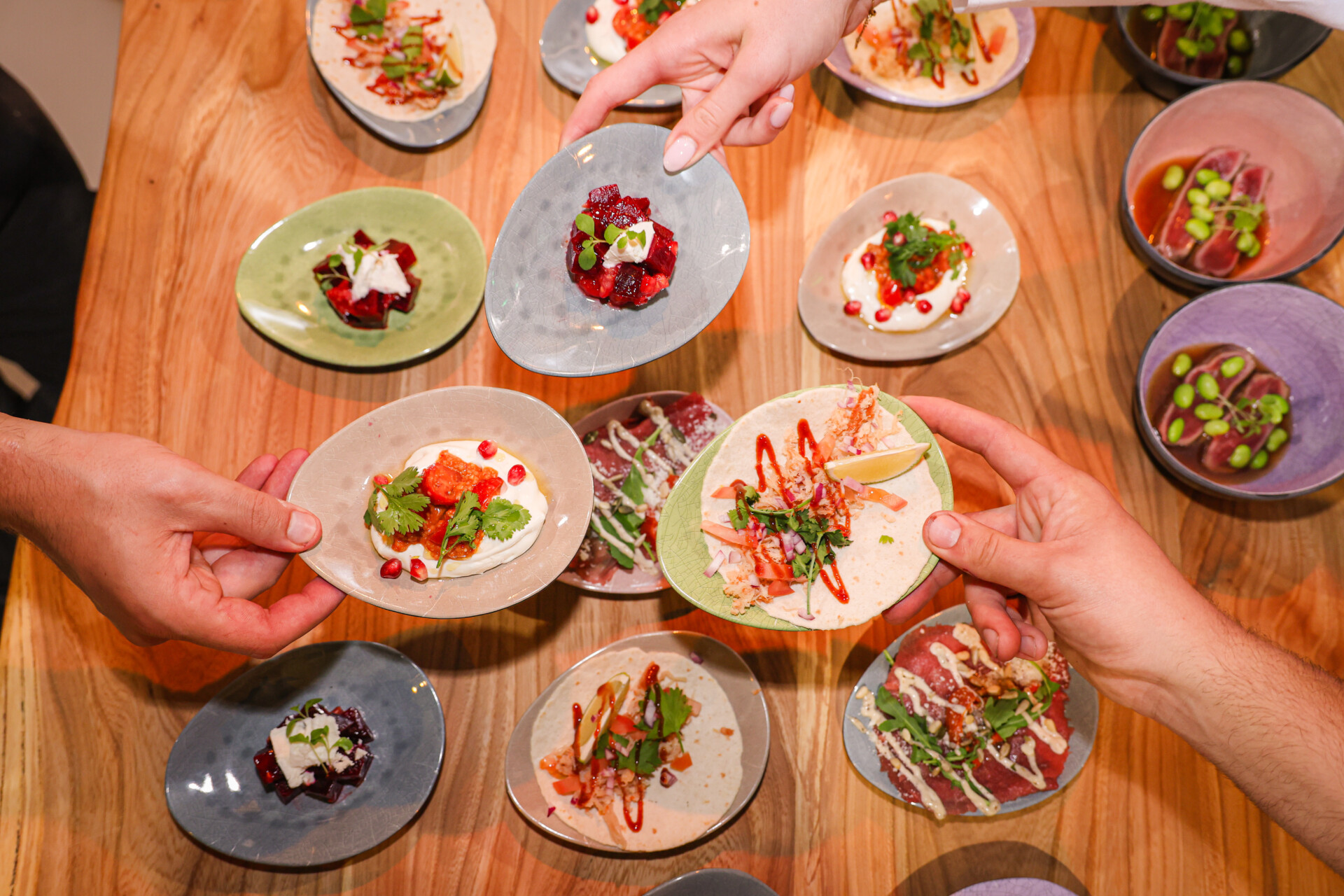 Handen serveren kleurrijke tapas en taco's op houten tafel