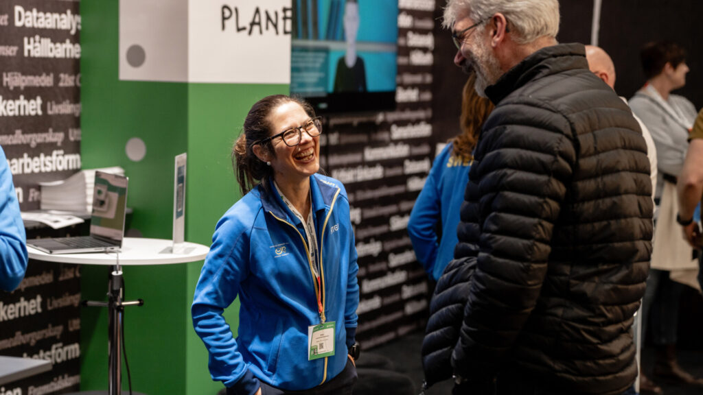 Glad utställare och besökare i en monter