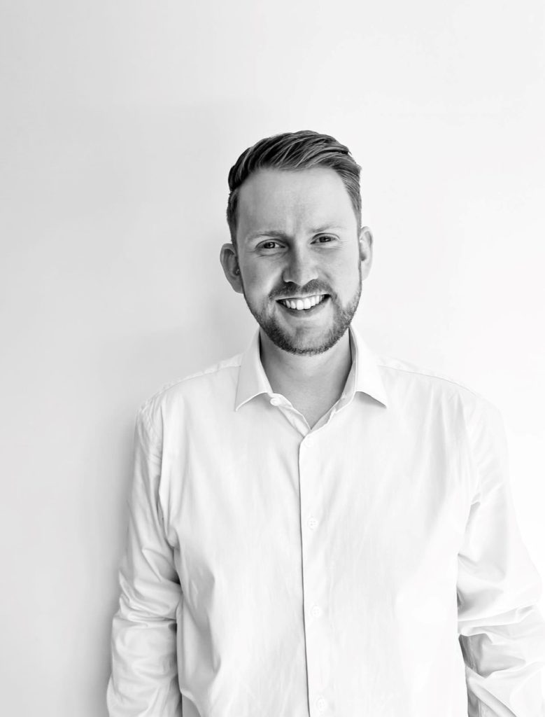 Josh b&w man smiling with plain background and white shirt