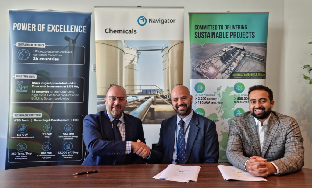 three men in suits shaking hands in front of roller banners