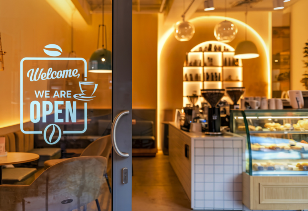 Open coffeeshop met verlichte toonbank en gebaksvitrine