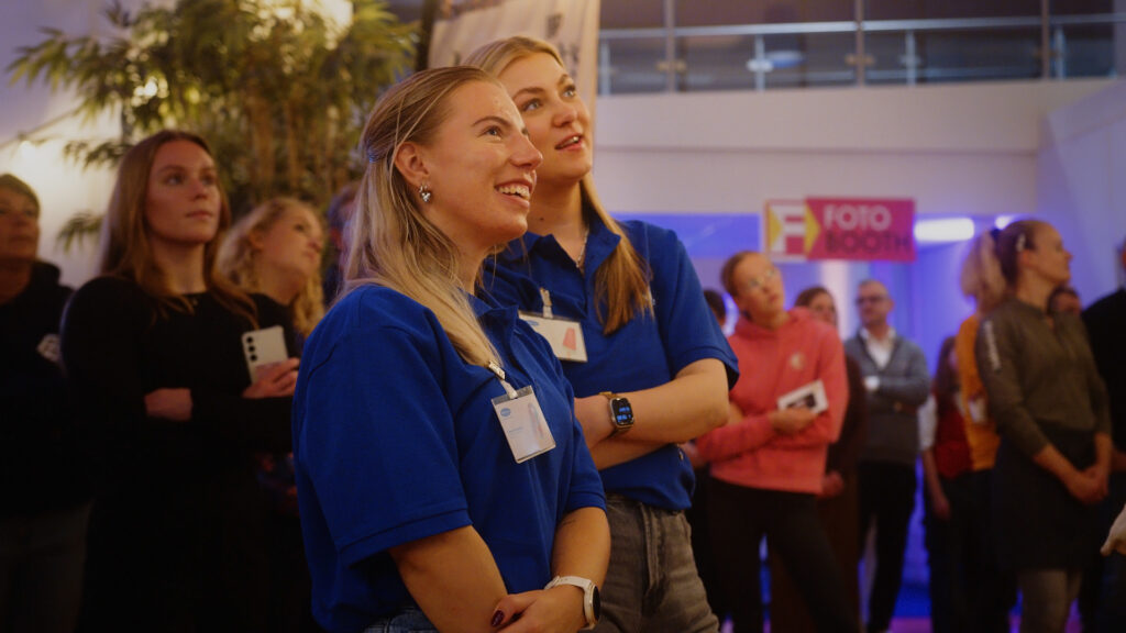 Bezoekers kijken aandachtig naar presentatie op evenement