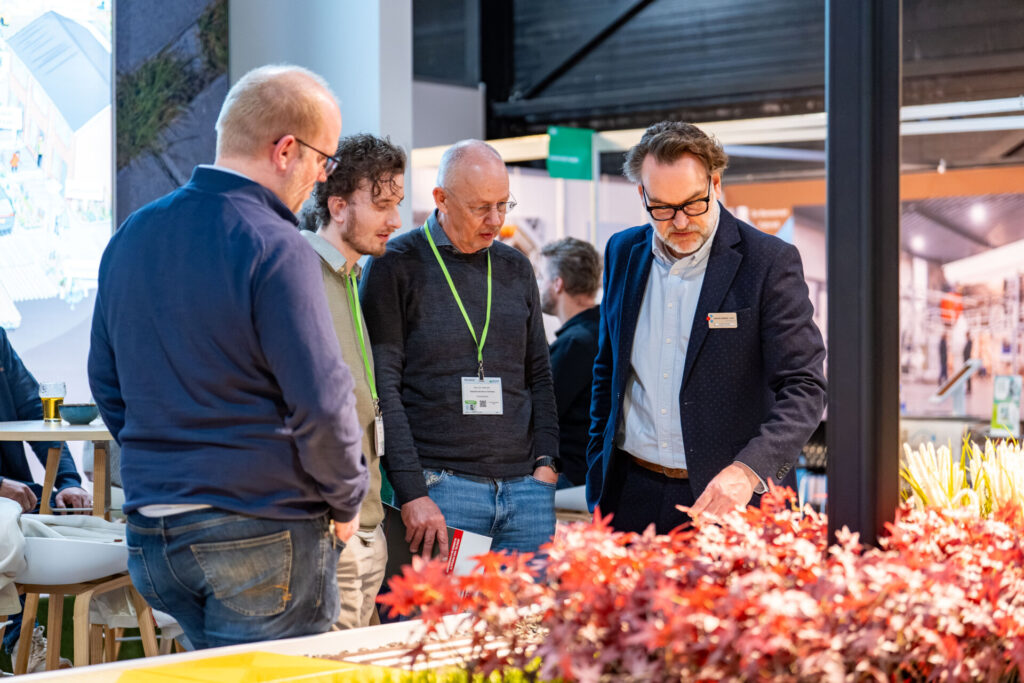 Vier mannen bekijken planten op een beursstand