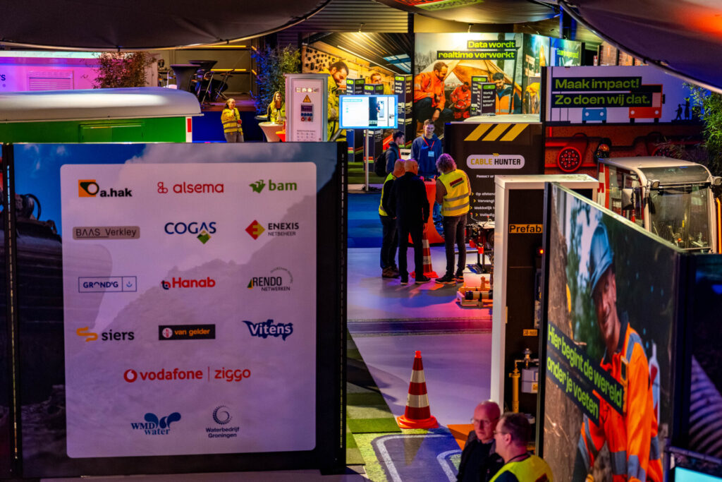 Bezoekers bij stands op infrastructuurbeurs met kabeldetectietechnologie