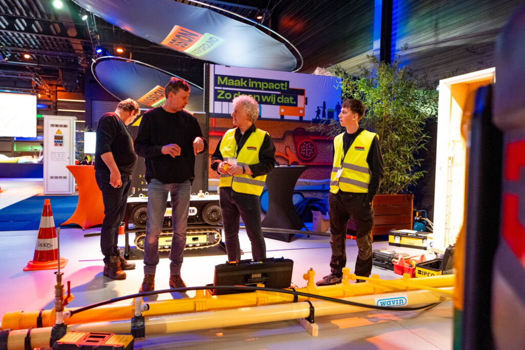 Bezoekers bekijken leidingtechniek op een vakbeursstand