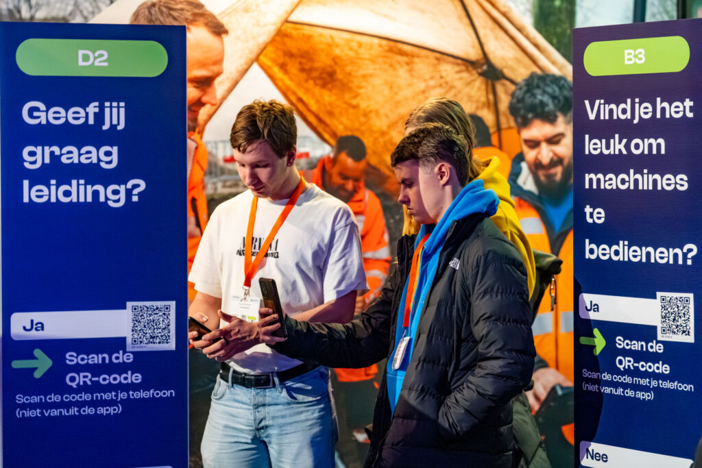Jongeren scannen QR-codes bij interactieve beursborden