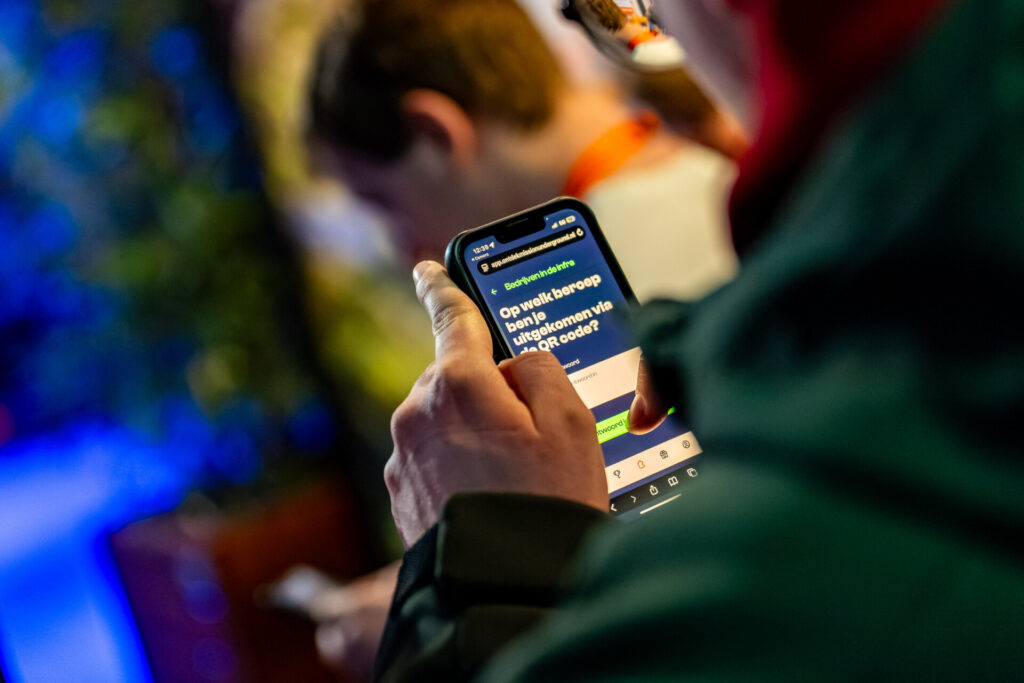 Persoon vult quizvraag in op smartphone tijdens evenement