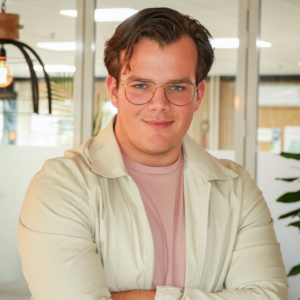 Jonge man met bril en beige jas in modern kantoor