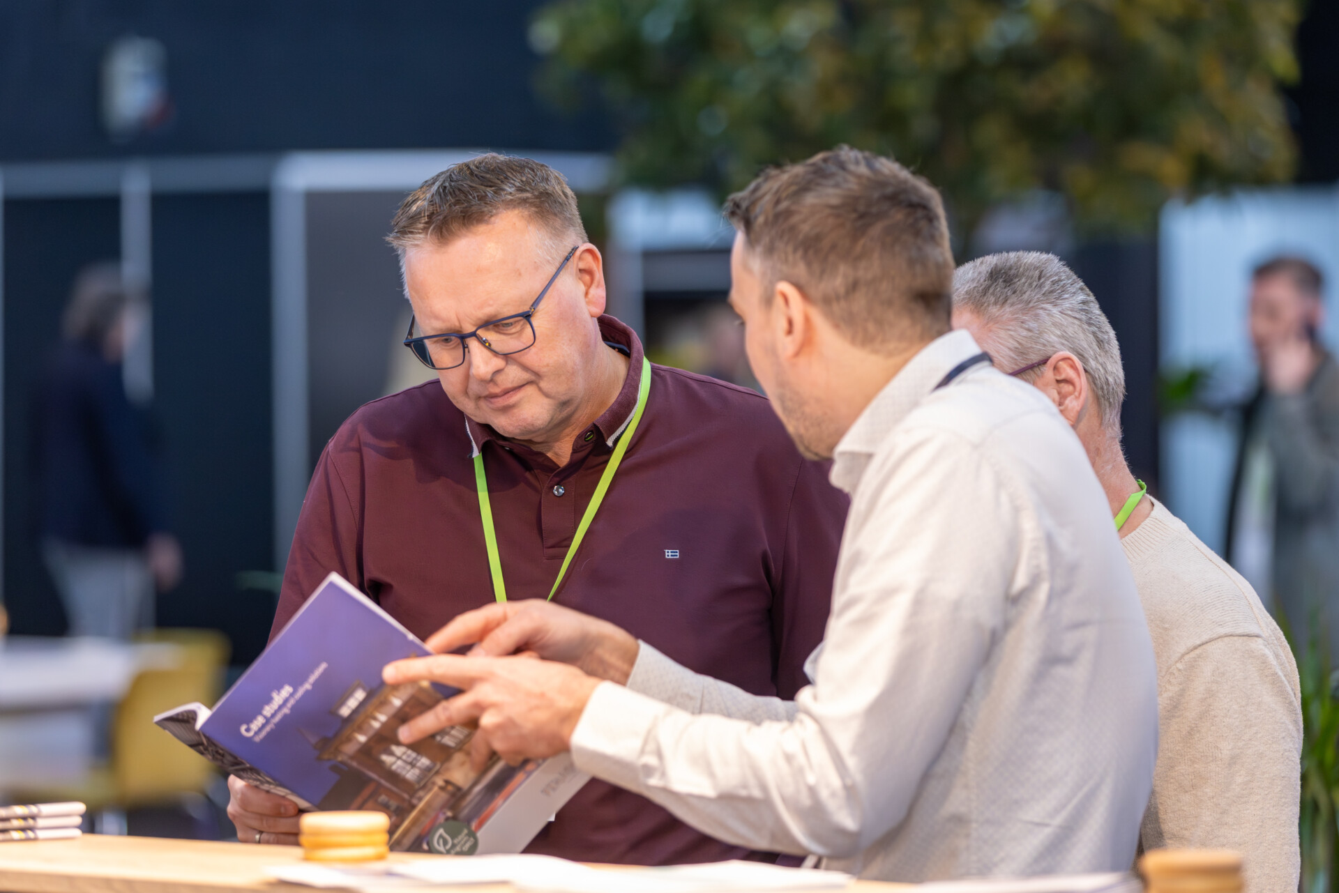 Drie mannen bekijken brochure op zakelijke beurs