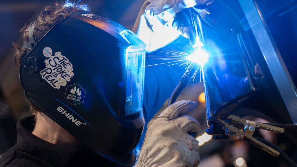 Lasser met beschermhelm werkt aan metalen constructie
