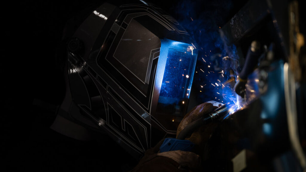 Lasser met donkere helm tijdens metaalbewerking