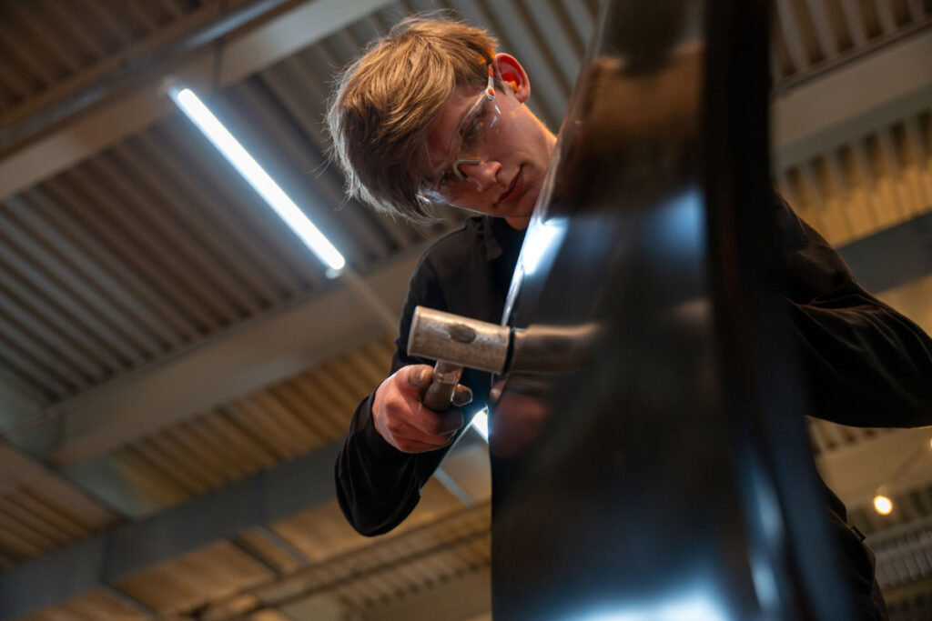 Jonge metaalbewerker hamert op glanzend metalen object