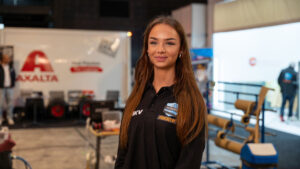 Vrouw in zwarte polo op beursstand van Axalta