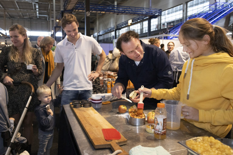 Bezoekers van de Familiedagen staan bij een kraam waar verschillende delicatessen worden bereid
