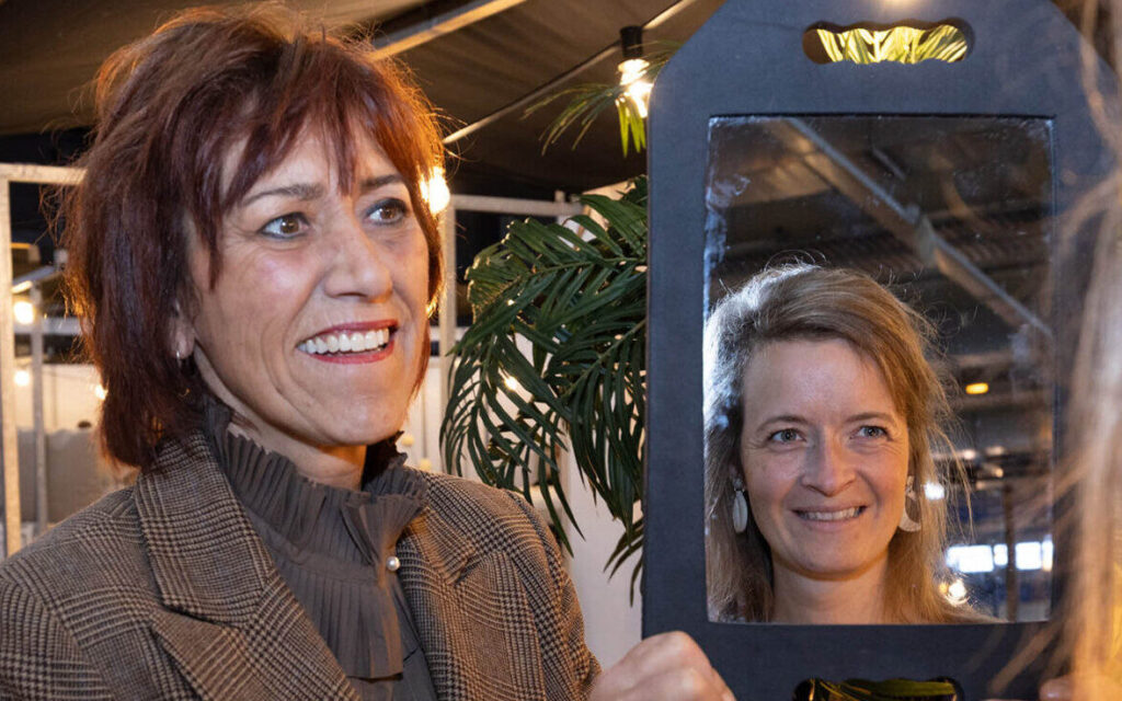 Vrouw houdt spiegel vast met reflectie van andere vrouw