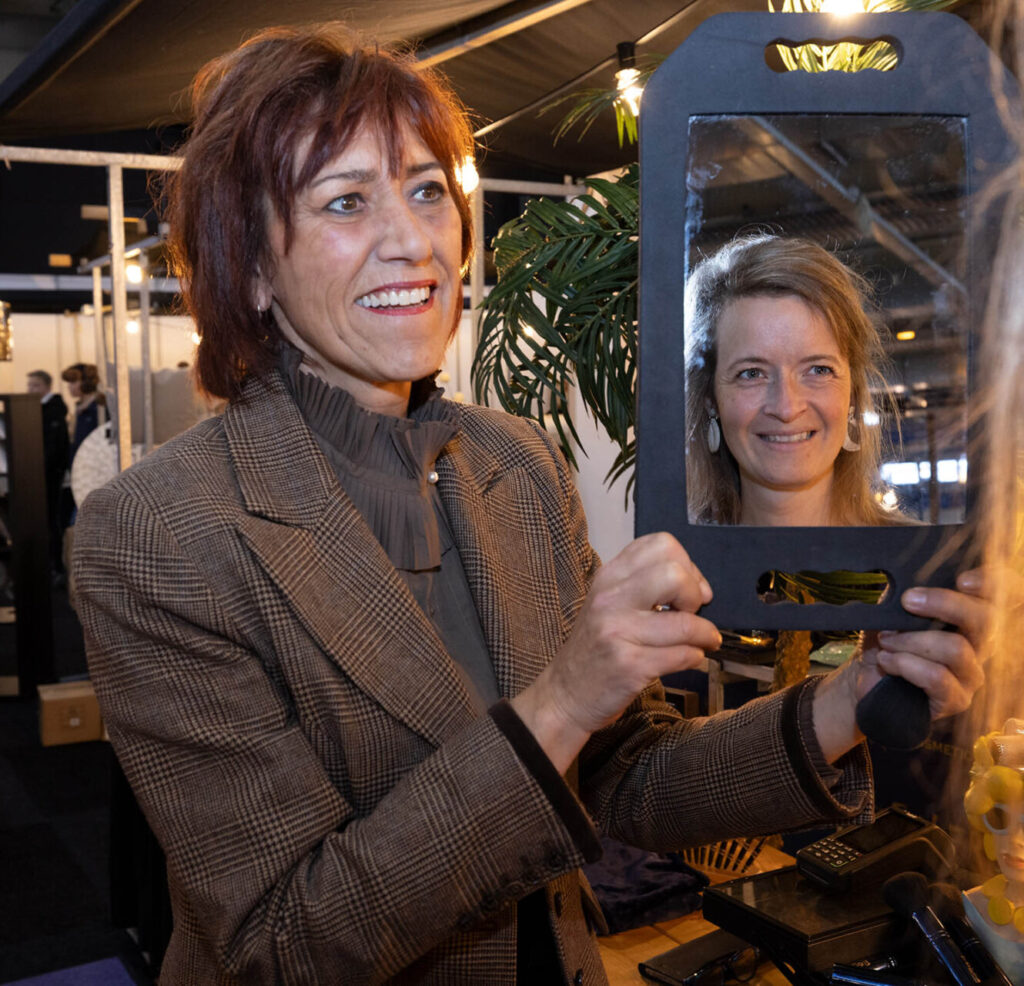 Vrouw houdt spiegel vast met reflectie van andere vrouw