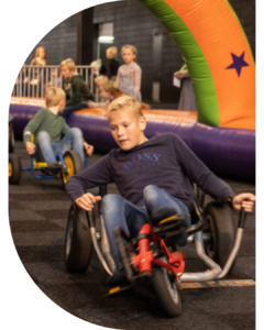 Kinderen racen op skelters bij een opblaasbare attractie.