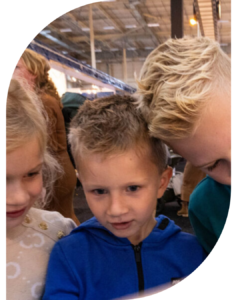 Drie kinderen poseren dicht bij elkaar in een hal