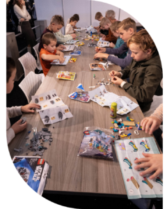 Kinderen bouwen LEGO-sets aan een lange tafel