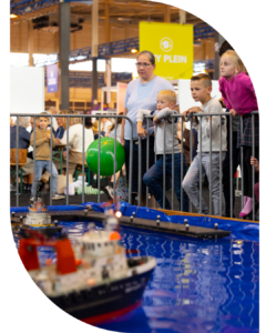 Kinderen bekijken modelboten bij een indoor evenement