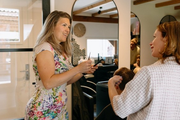 Kapster bespreekt kapsel met klant in salon