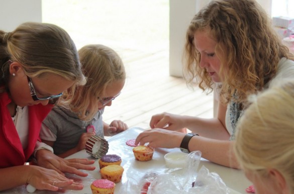 Vrouwen en kinderen versieren cupcakes aan tafel