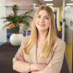 Glimlachende vrouw in beige blazer op kantoor
