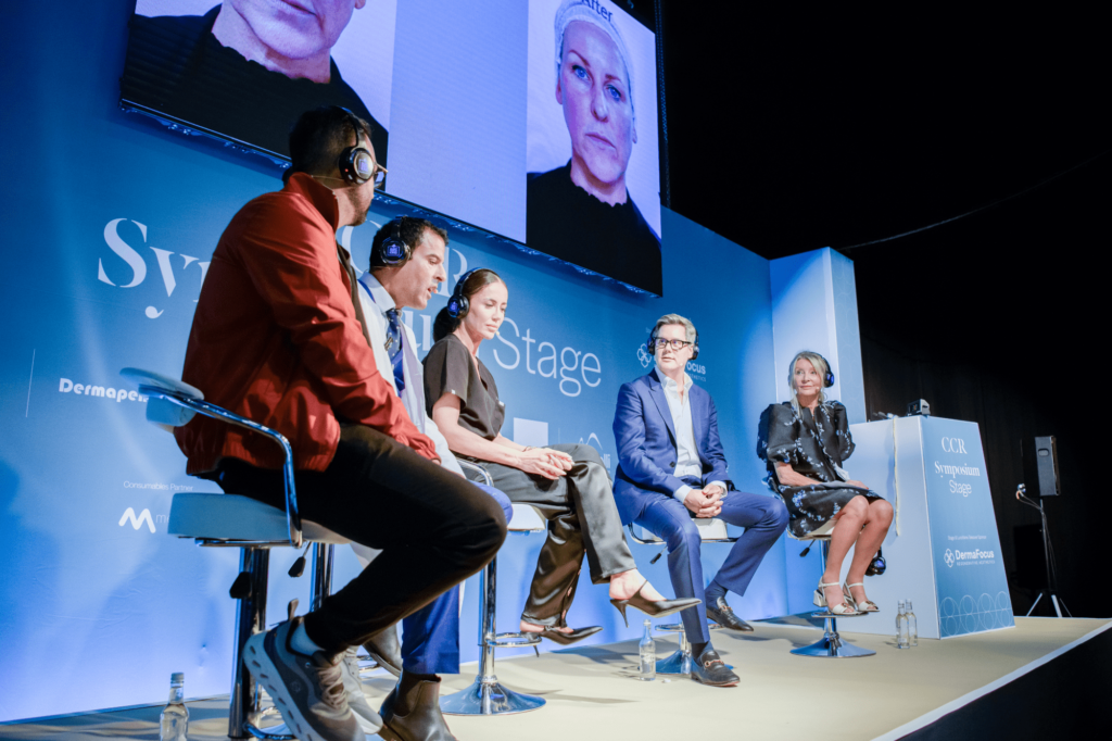Symposium stage speaking panel with 5 speakers with a blue background