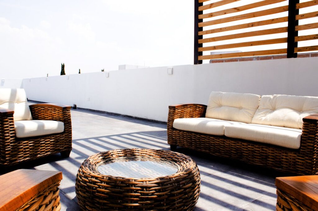 Rotan loungeset met witte kussens op een terras.