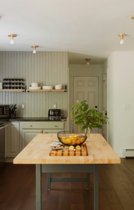 Een nette, moderne keuken met lichtgroene keukenkasten en gouden accenten.