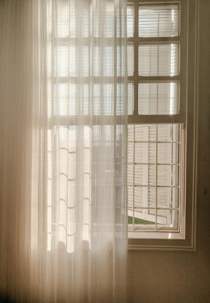Groot raam met semi-transparant gordijn half voor het raam.