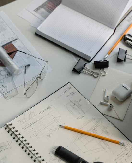 Architecturale schetsen met op een bureau met ernaast potloden, een meetinstrument, ...