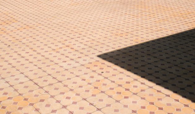 Close-up van roodbruine tegels met een ruitpatroon.