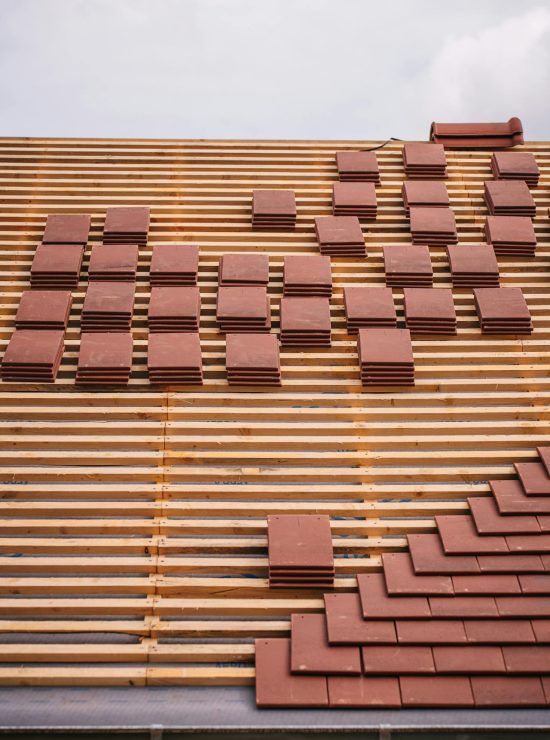 Een dak waar je vooral alle houten balken ziet met hier en daar een stapel roodbruine dakpannen.