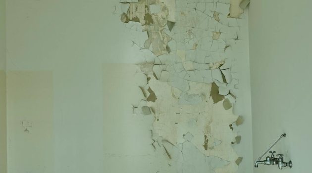 Een muur vanbinnen in een woning met afbladerende verf