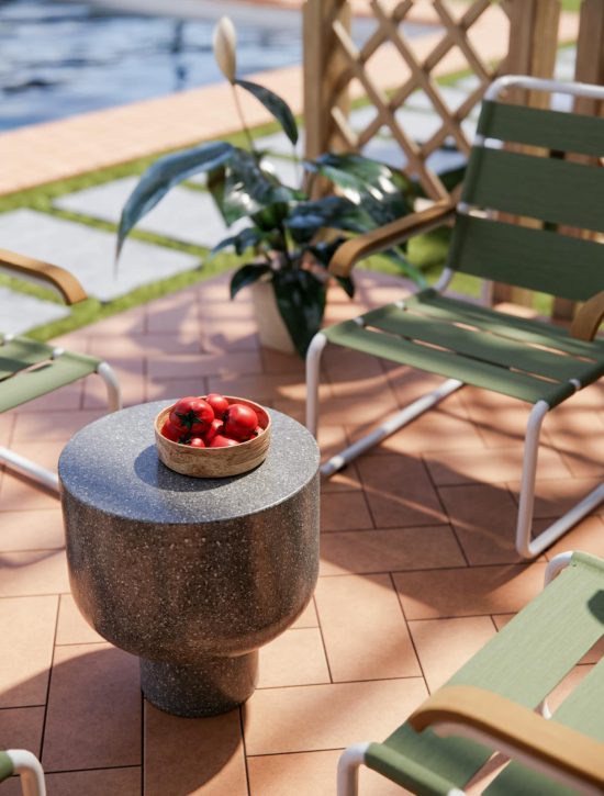 Foto van een terras met terracotta tegels met een terrastafel een een mand erop. Op de achtergrond bevinden zich groene terrasstoelen naast een zwembad.