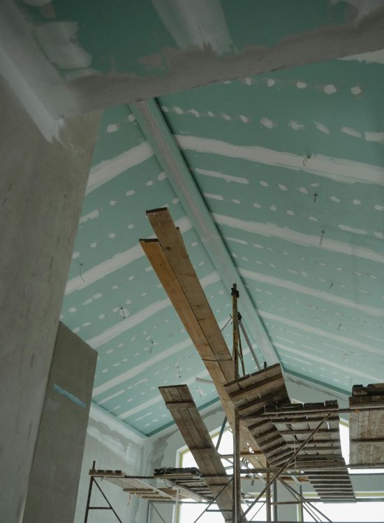 Foto van de binnenkant van een dakrenovatie met een paar houten stellingen.