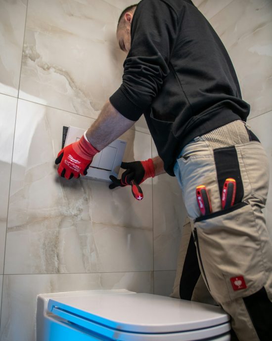 Loodgieter of klusjesman die de drukknop van een toilet installeert.