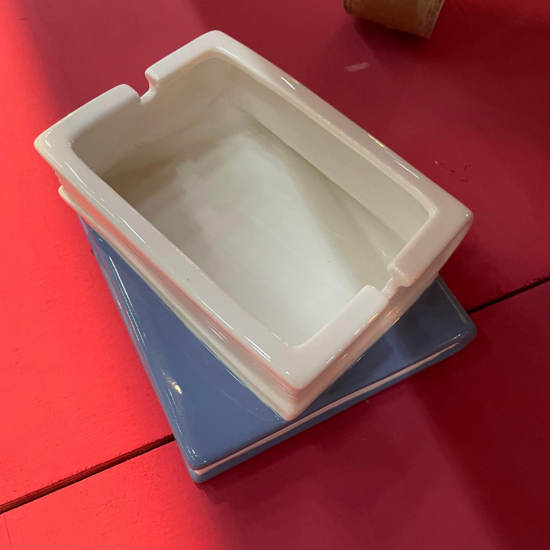 Witte keramische asbak op blauwe onderzetter