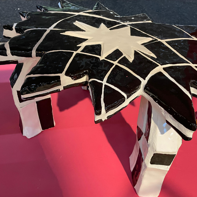 Zwart-wit mozaïeksculptuur met sterpatroon op roze sokkel
