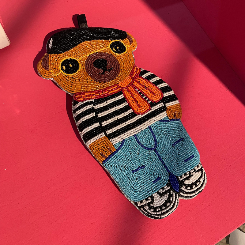 Kralenpop met baret op roze tafel