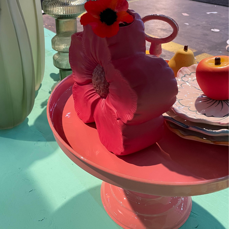 Roze hibiscus-theepot op taartplateau met fruit