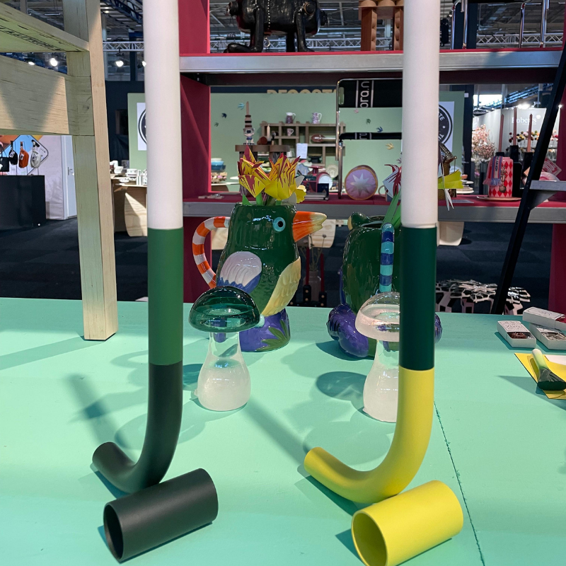 Kleurrijke designkandelaren en glazen dieren op een beursstand
