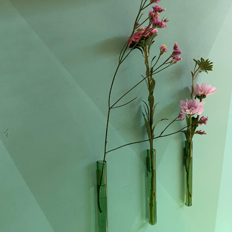 Drie glazen wandvaasjes met roze bloemen