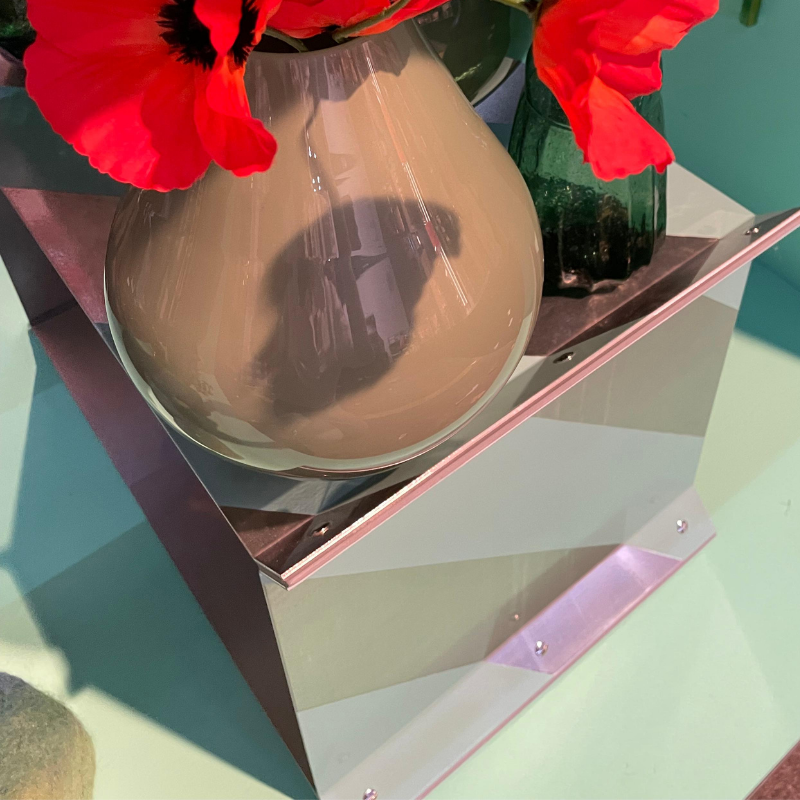 Rode bloemen in glazen vaas op spiegelvoet