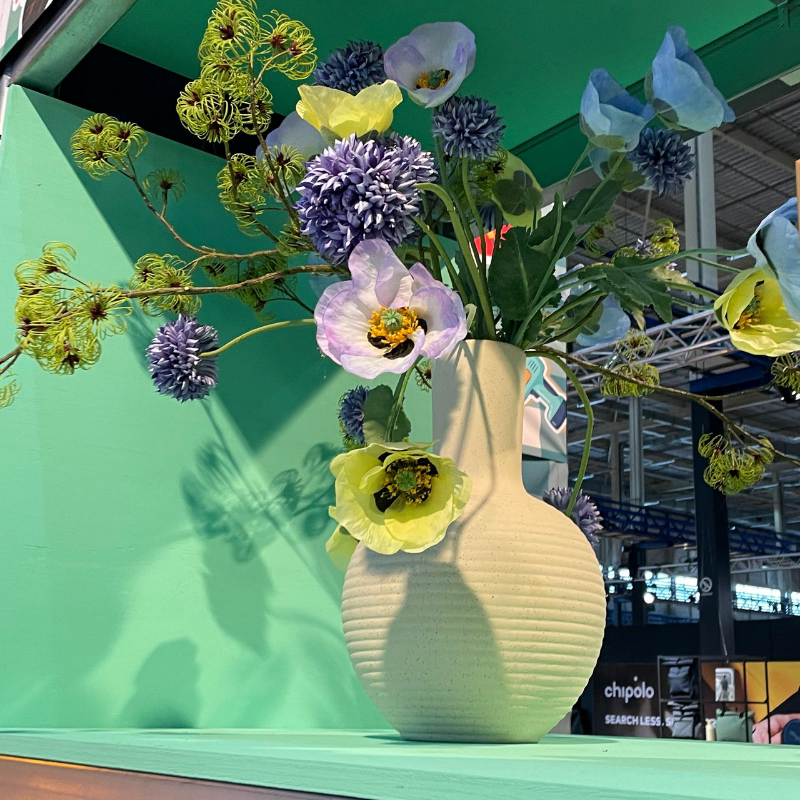 Beige vaas met kleurrijk bloemboeket tegen mintgroene achtergrond